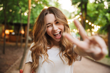 Close up of cheerful young girl showing peace gesture