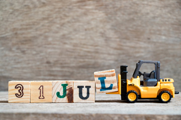 Toy forklift hold block l to complete word 31 jul on wood background (Concept for calendar date in...