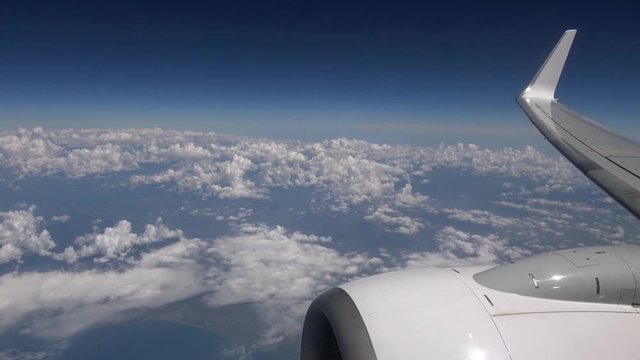 4K. Beautiful clouds seen through the window of airplane. Turbine and aircraft wing. Travel in plane. View of traveler in cabin-Adrian