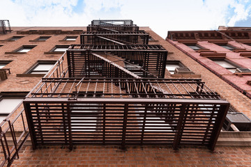 Typical old brick apartment building with fire escapes stairs in New York city