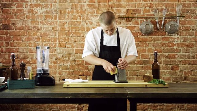 The cook rubbing parmesan cheese on the metal grater for pesto sauce. 4K