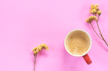 Red coffee cup with dried little flowers on pink background, morning desk office 