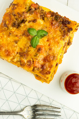 Italian Lasagna with Minced Beef, Bolognese Sauce and Basil on White Plate
