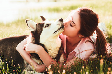 A girl is kissing a dog of the breed of husky.