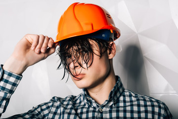 Builder with a wet head.Handyman in helmet with screwdriver in his hand.Stroitel, designer, designer, architect. Repair in the apartment. Services.Attractive young man in an orange construction helmet