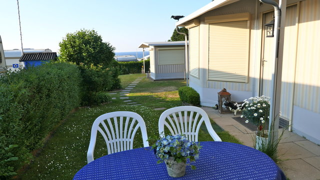 Caravan mit einer festen Veranda aus Markisenstoff, Glasschiebefenster und Rolll&auml;den auf einem deutschen Campingplatz. Komfortabel und gut gepflegt. Die Jalousien sind geschlossen.
