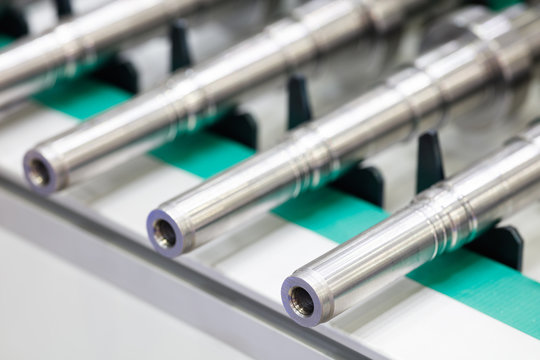 Manufacture of metal products, shafts or bushings lie on a conveyor belt, industrial concept background