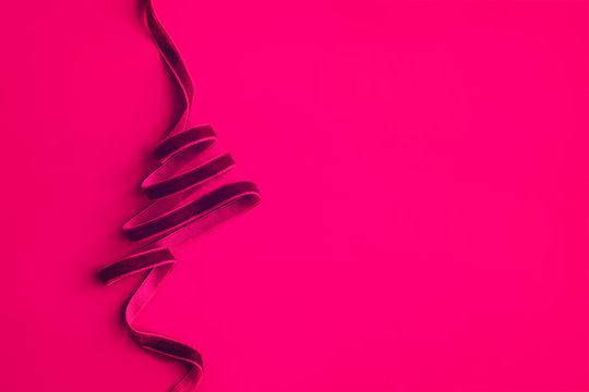 Christmas tree made with dark pink velvet ribbon curles on colored background. Minimalism concept. Copy space for text, horizontal