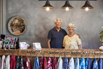 Portrait Of Senior Store Owners Standing Behind Cash Desk