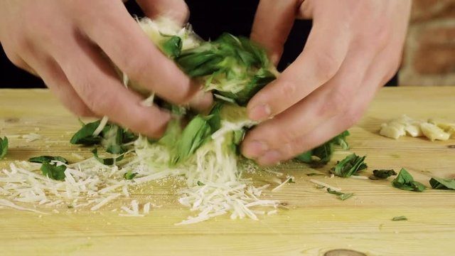 Preparation of pesto sauce. Grated parmesan cheese and fresh chopped basil on wood cutting board. 4K
