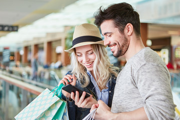Paar beim Shopping nutzt Smartphone App - obrazy, fototapety, plakaty