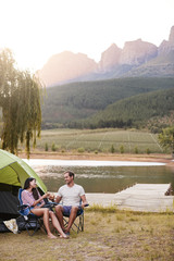 Couple Enjoying Camping Vacation By Lake Making A Toast