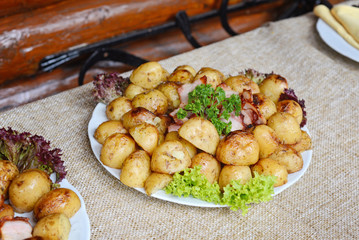 grilled potatoes with bacon served on white plate with lettuce and parsley leaves