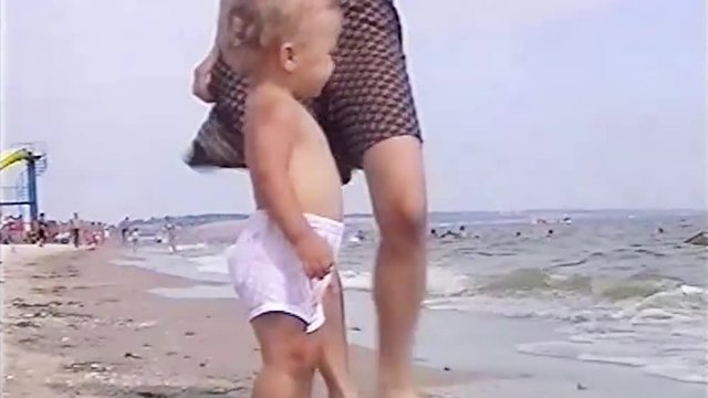 VHS footage from little happy boy run along the beach and smile. Old home family movie of cute baby playing and enjoying on beach.