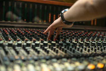 Hand of the mixing engineer on the audio console