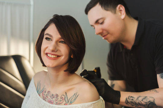Tattoo artist working with needle on clients body