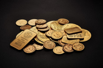 Yellow gold bars and coins isolated on black background