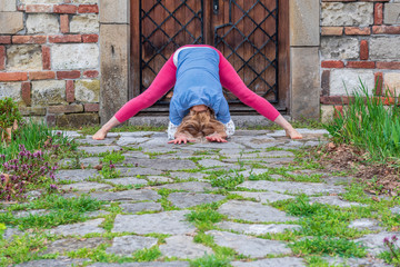 Attractive blond woman doing yoga poses outdoor,  in front of old fortress. Longevity concept 
