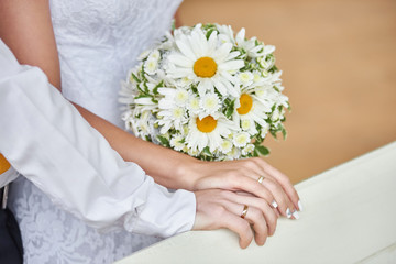 Hands newlywed couple with wedding rings and bridal bouquet