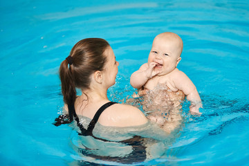 Mother teach baby to swim in water pool. Swimming lessons for children