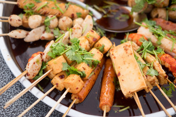 Variety of meatballs in sweet and sour spicy sauce on tray