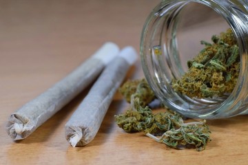 Marijuana buds, jar, money and joints on the table. Drugs and addiction concept