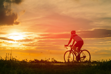 Fototapeta na wymiar Backside of cyclist ride bicycle on sunset time in public park. Sport and active life concept.