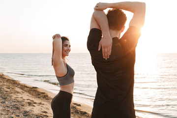 Fit young couple stretching hands while working out