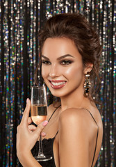 ..Portrait of a beautiful girl with a smile on her face, bright make-up and hairstyle, a holiday theme of Christmas and New Year, holding a glass of wine in her hands. Photographed on a brilliant