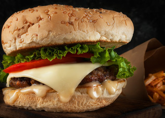 A delicious hamburger with a juicy cutlet, cheese, tomato and salad.