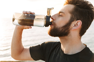 Close up of a thirsty young sportsman drinking water