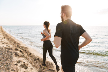 Back view of a fit young couple jogging together