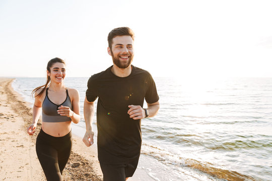 Happy young couple jogging together on a beach
