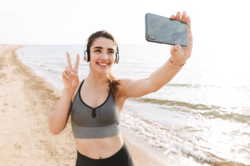 Smiling young sportswoman standing at the beach