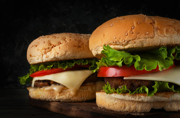 A delicious hamburger with a juicy cutlet, cheese, tomato and salad.