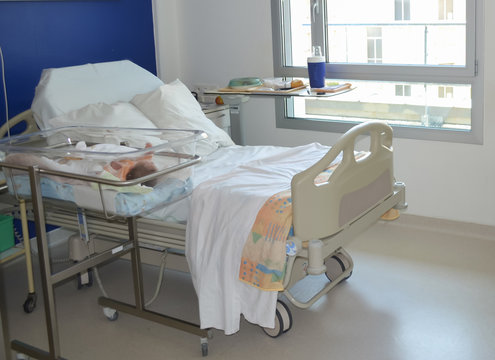 Empty Hospital Bed And Newborn Baby Near The Bed