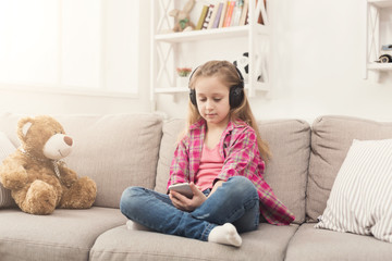 Little girl and teddy bear listening to music