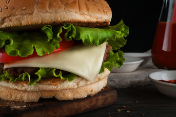 A delicious hamburger with a juicy cutlet, cheese, tomato and salad.