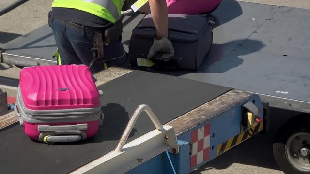 4K. A technical staff is loading baggage on conveyor to commercial airline airplane. Baggage on conveyor belt airplane. Departures terminal-Adrian