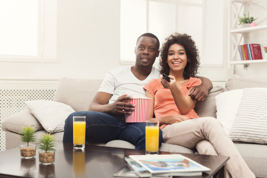 Happy african-american couple watching TV at home