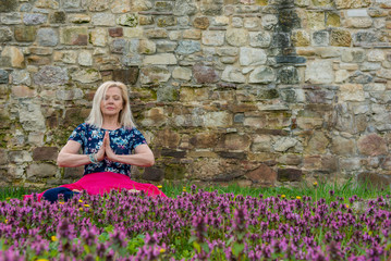 Attractive mature woman doing yoga outdoor in park, enjoying nature and fresh air. Longevity concept