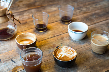 Different cups of coffee on wooden table, top view, vintage style