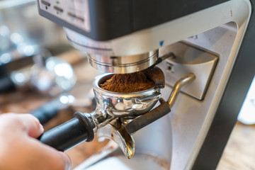 Barista grinding coffee beans using coffee machine