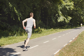 Young man jogging on treadmill in park, copy space
