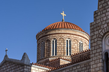 Fototapeta na wymiar Dome of old byzantine greek orthodox church cathedral with red roof, golden Christian cross and blue sky in the background - concept religion god Christianity orthodox theology faith architecture