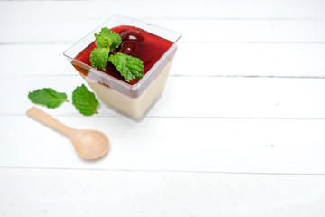 Panna Cotta Strawberry in a glass Placed on a white table. There is a wooden spoon on the side. And...