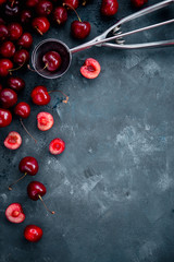 Cherries and ice cream spoon on a grey concrete background, summer berries concept with copy space. Making dessert flat lay in neutral color tones