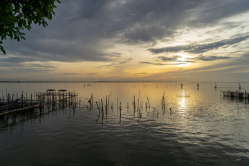 Naklejka na ściany i meble Sunset view from Songkhla lake with traditional fish trap and tree.