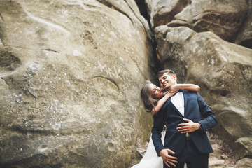 Gorgeous bride, groom kissing and hugging near the cliffs with stunning views