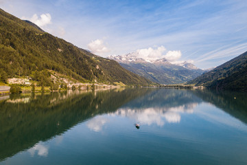 Naklejka na ściany i meble Isolated boat on the alpine lake, lake of Poschiavo in the Canton Grisons, Switzerland